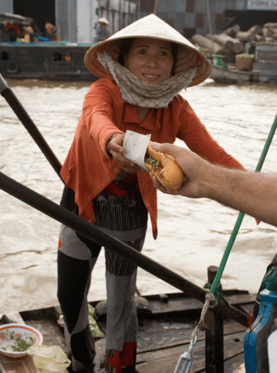 lady handing someone Vietnamese sandwiches